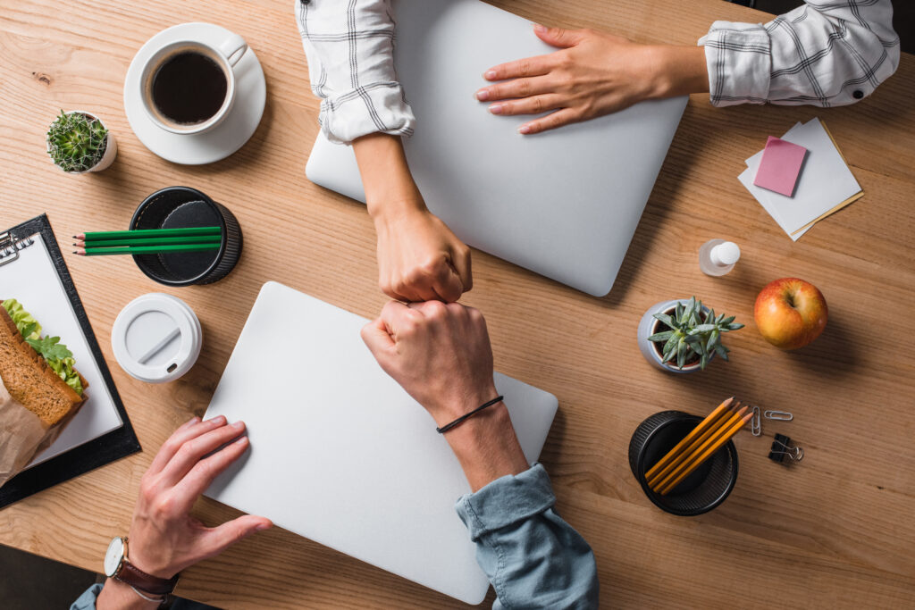 A top down view of coworkers fist bumping over a desk